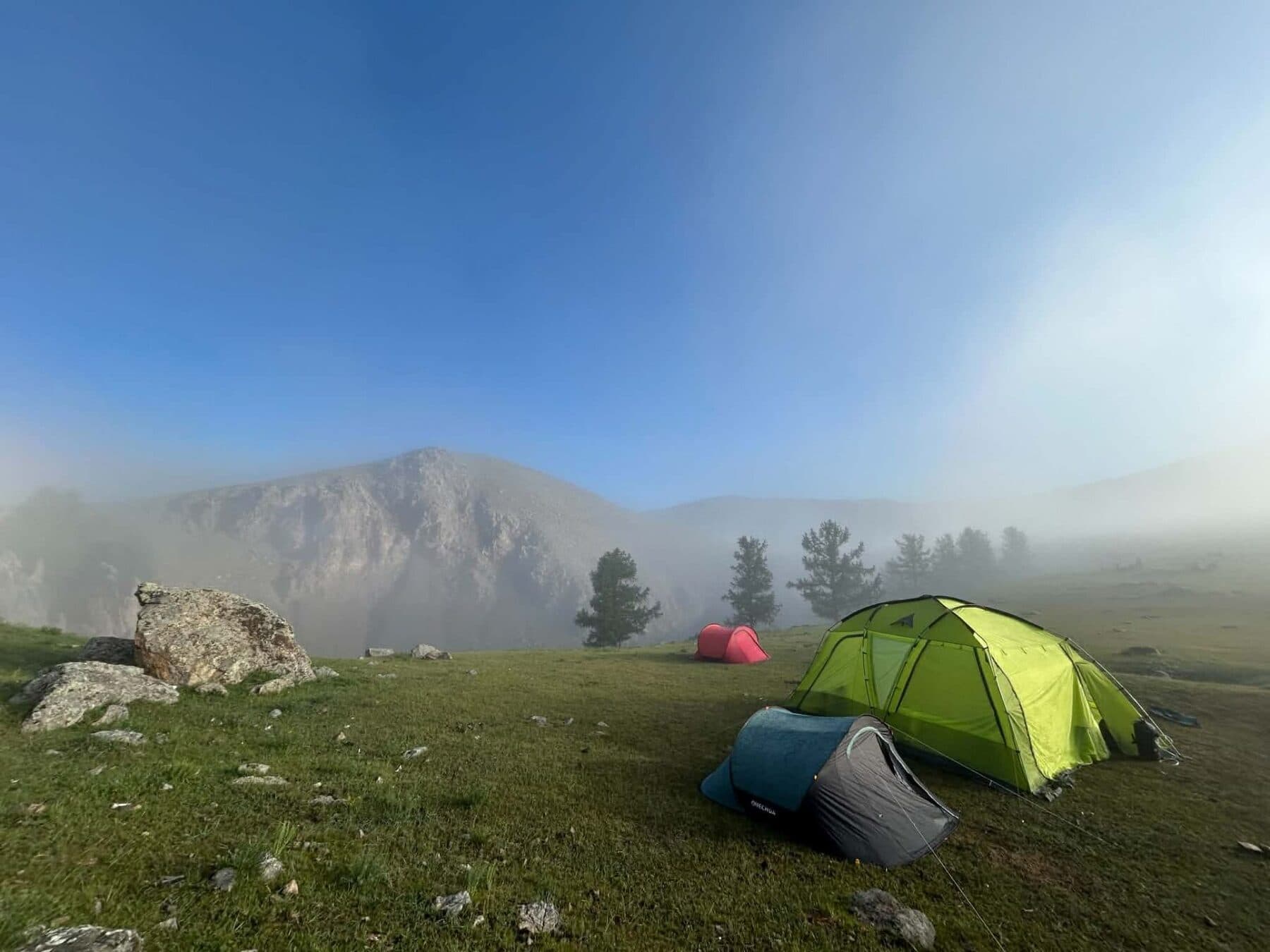Tents pitched below a misty mountain