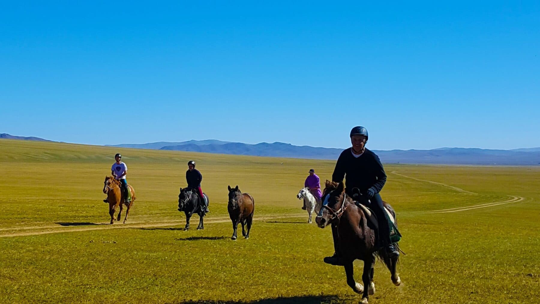 Riders cantering across golden steppe