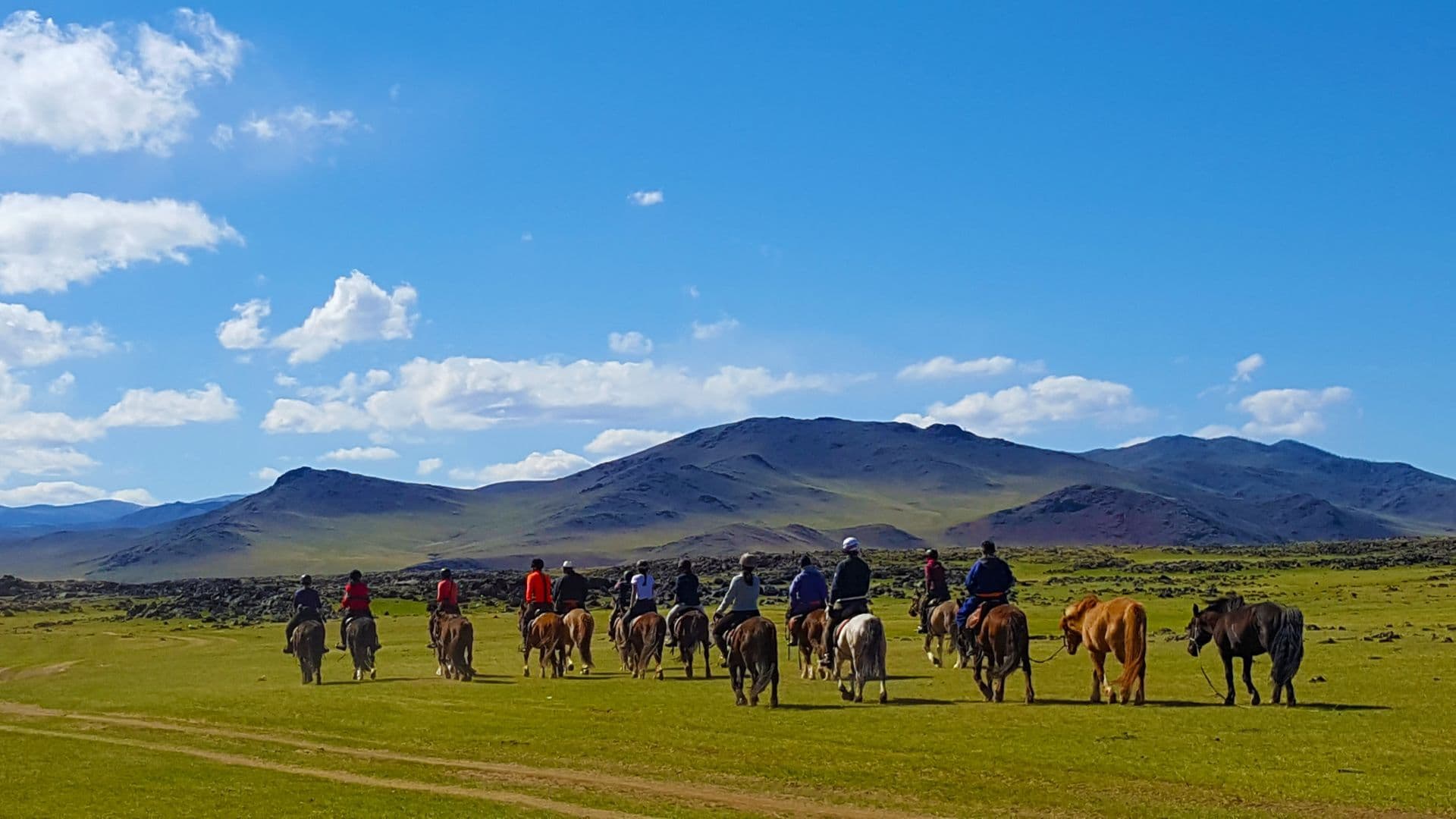 A group of riders heading across the steppe toward the mountains